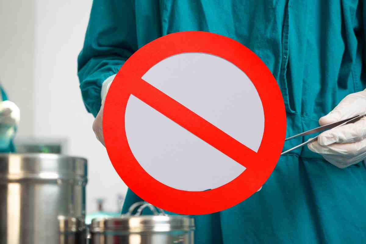 medico con disinfettante e davanti un segnale di divieto