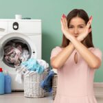 lavatrice con panni sparsi, donna che fa segno x con le braccia