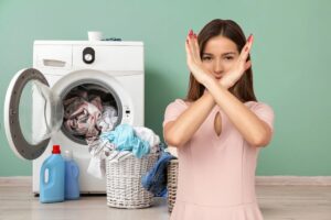 lavatrice con panni sparsi, donna che fa segno x con le braccia
