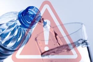 bottiglia che versa acqua in un bicchiere con segnale pericolo