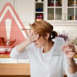 cucina, con segnale pericolo e donna con occhi coperti con una mano che tiene in mano uno scontrino