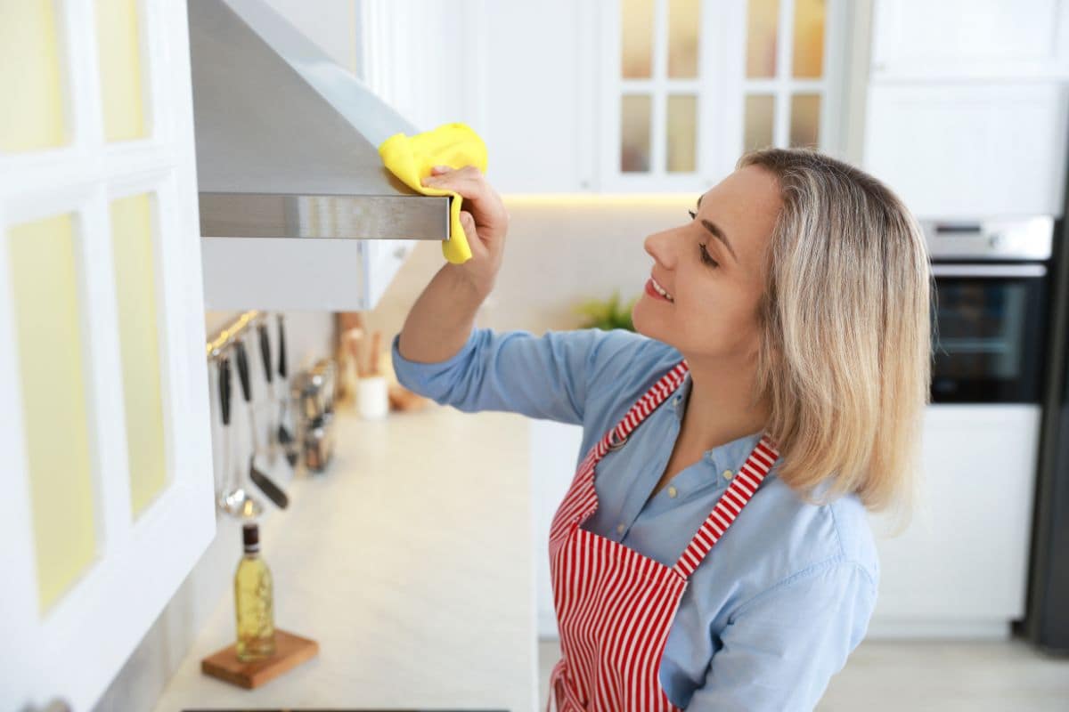donna che pulisce la cappa in cucina