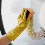 mano pulisce vetri di casa