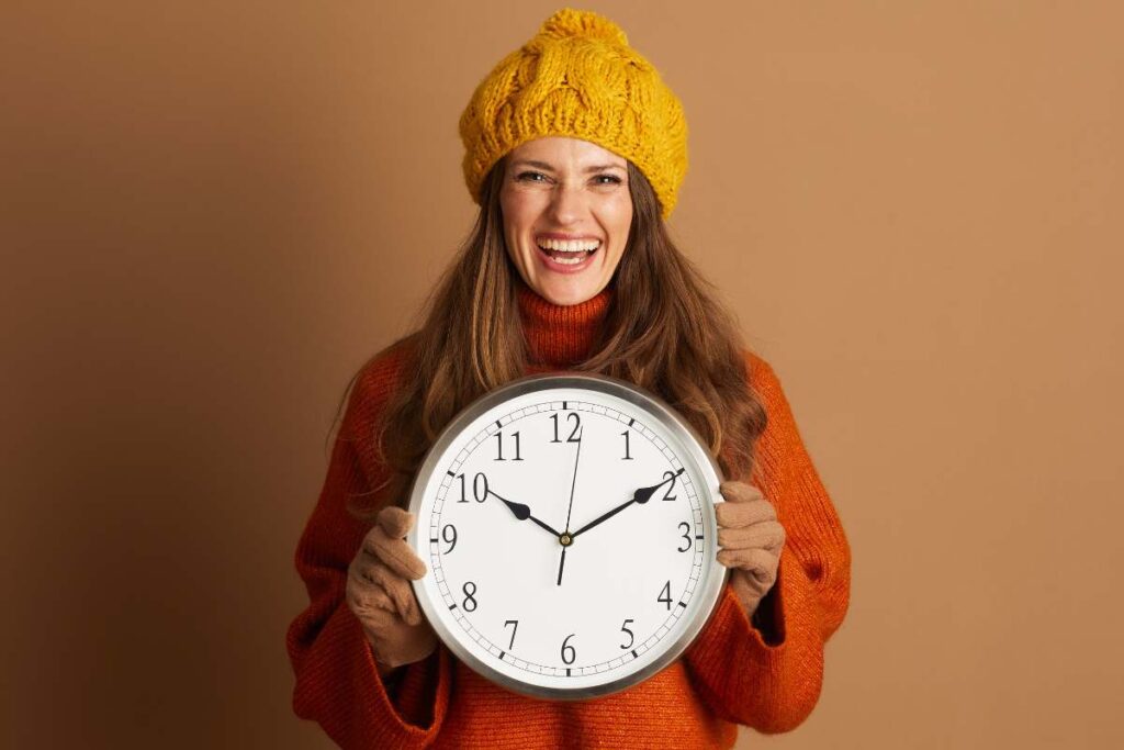 donna vestita autunnale con orologio in mano