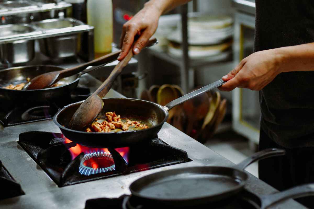 persona cucina con padella di ghisa