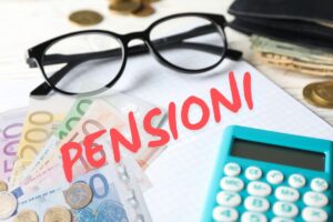 foglio bianco con scritta pensioni in rosso, occhiali da vista, calcolatrice e banconote e monete euro
