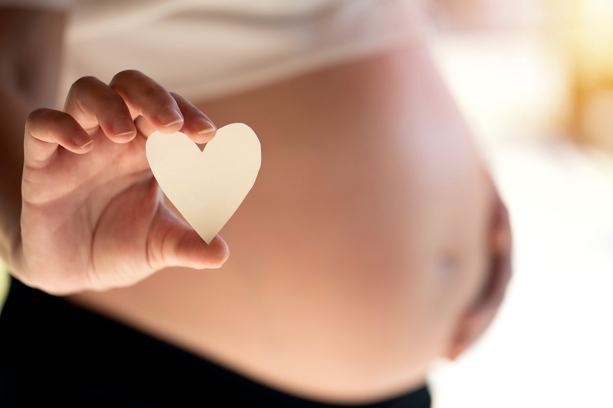 donna incinta con in mano un cuoricino di carta