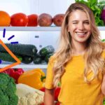 donna felice davanti a un frigo pieno di frutta e verdura