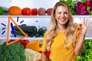 donna felice davanti a un frigo pieno di frutta e verdura