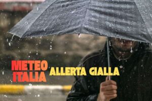 uomo con ombrello sotto la pioggia con scritta meteo italia allerta gialla