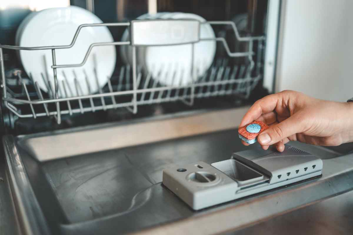 persona prepara la lavastoviglie coi piatti