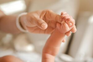 mano di una mamma che tiene la manina del neonato
