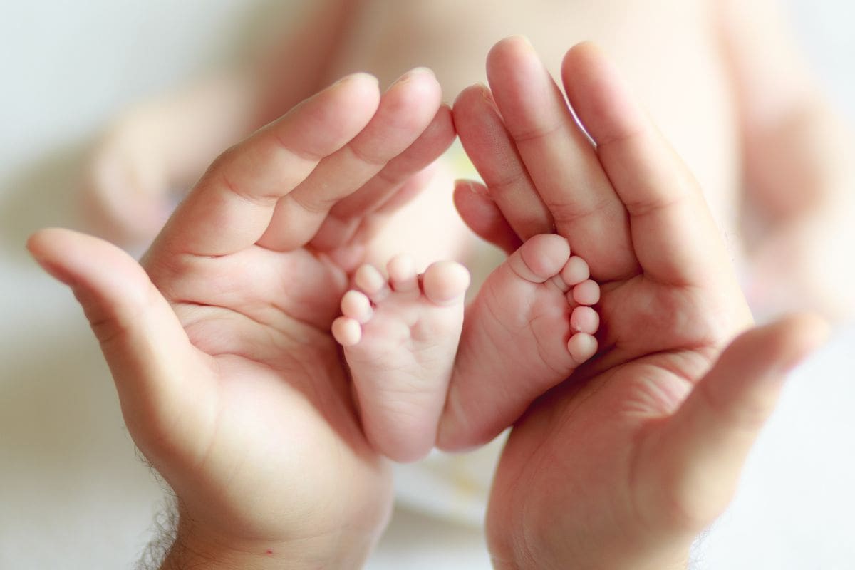 mani della mamma che tengono piedi del neonato