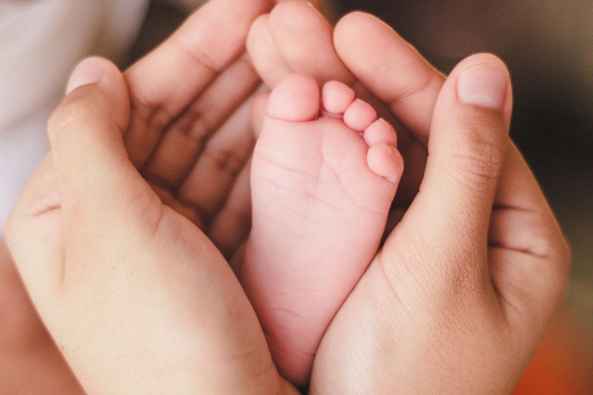 mani della mamma che stringono piedino figlio