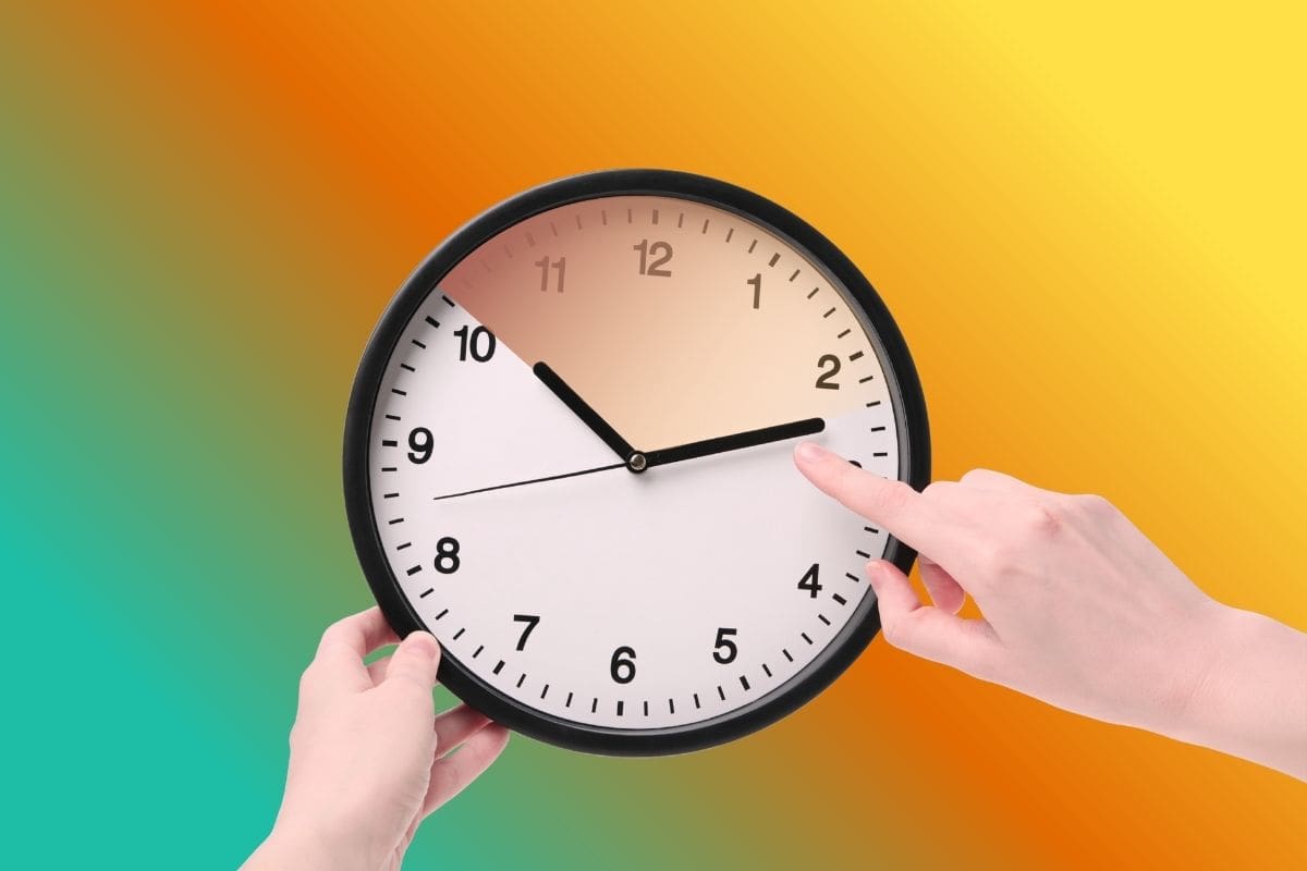 due mani che tengono orologio da parete rotondo con un dito che sposta lancetta