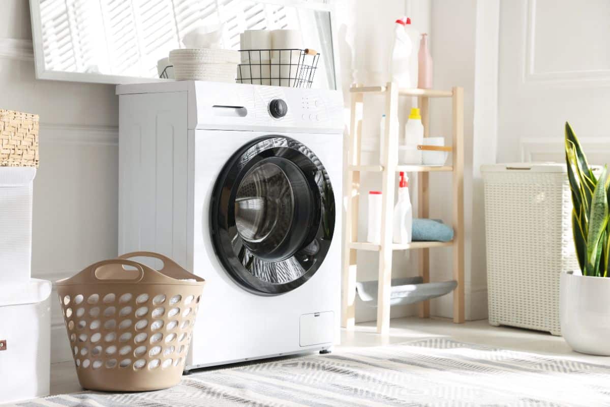 lavatrice con vicino mobiletto con detersivi e cesta panni