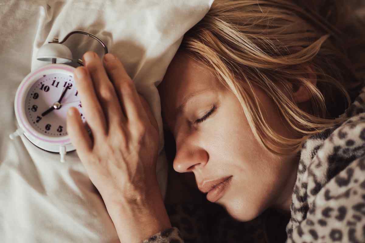 donna dorme con una sveglia sopra il cuscino
