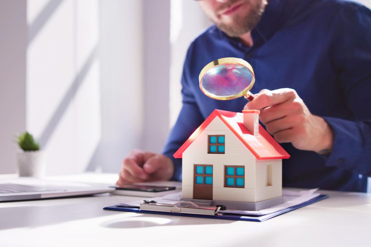 uomo guarda casetta con lente di ingrandimento