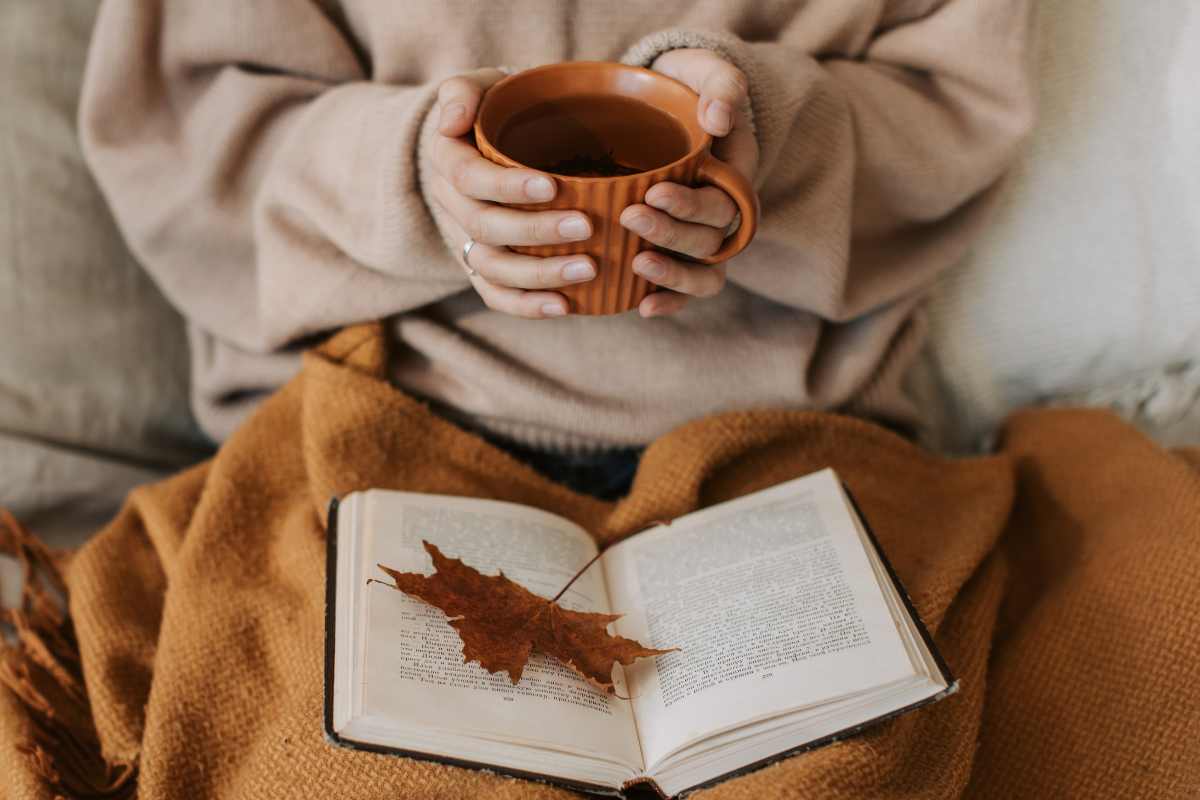 donna con tisana libro e foglia secca