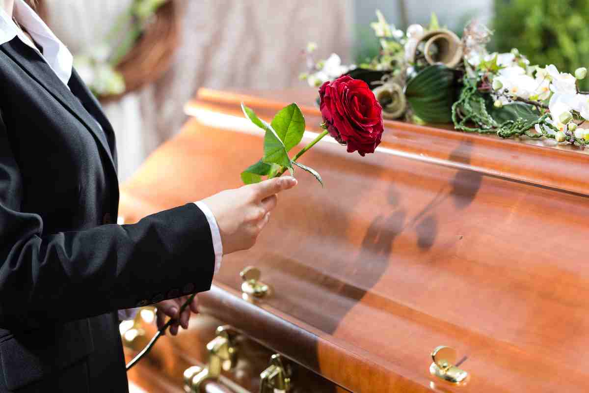 persona posa fiore su una bara