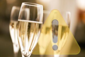 tre calici con prosecco e segnale pericolo