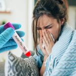 donna influenzata con mano con guanto che tiene una provetta con test aviaria