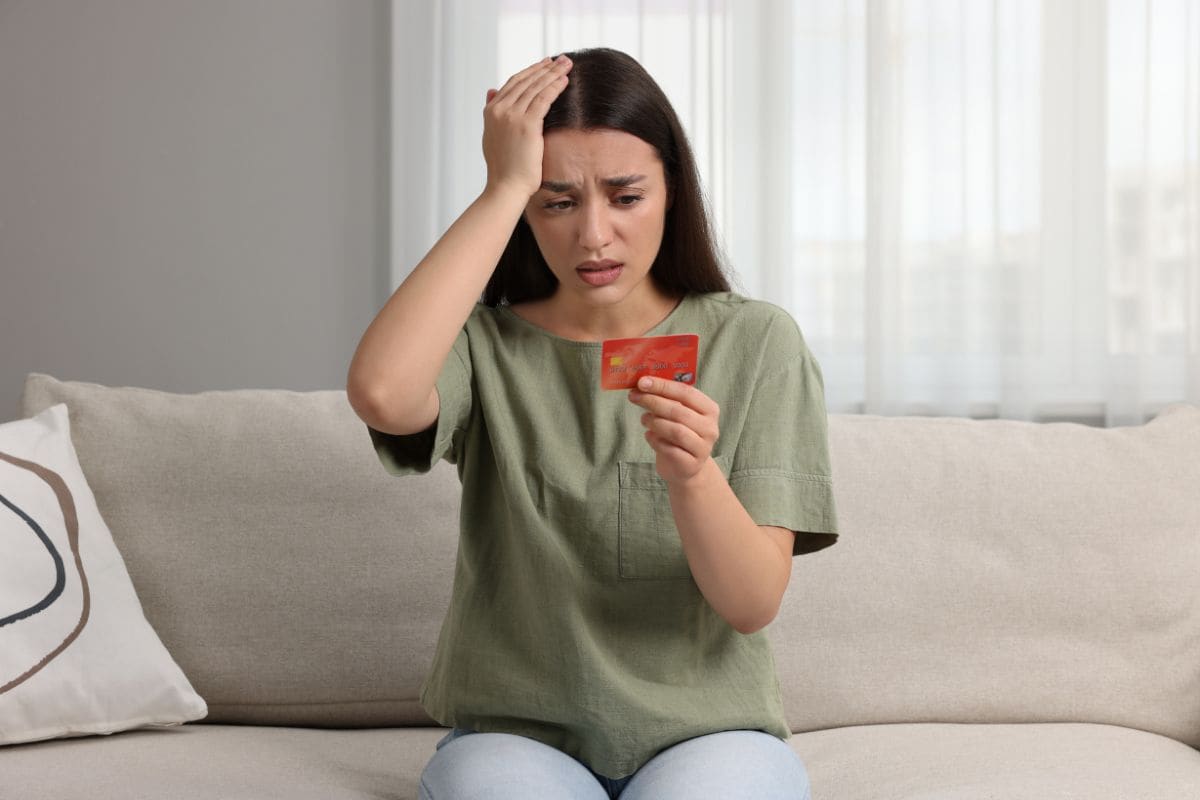 donna perplessa guarda la sua carta di debito/credito