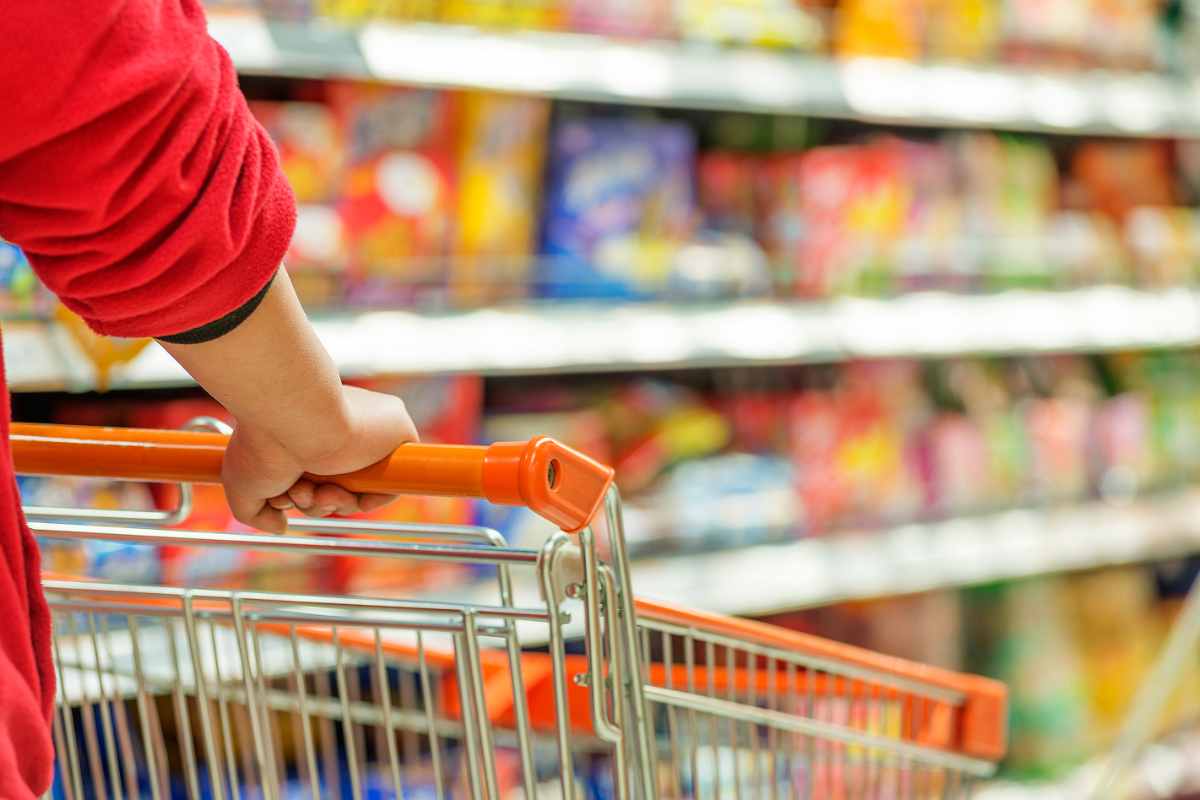 uomo spinge carrello al supermercato